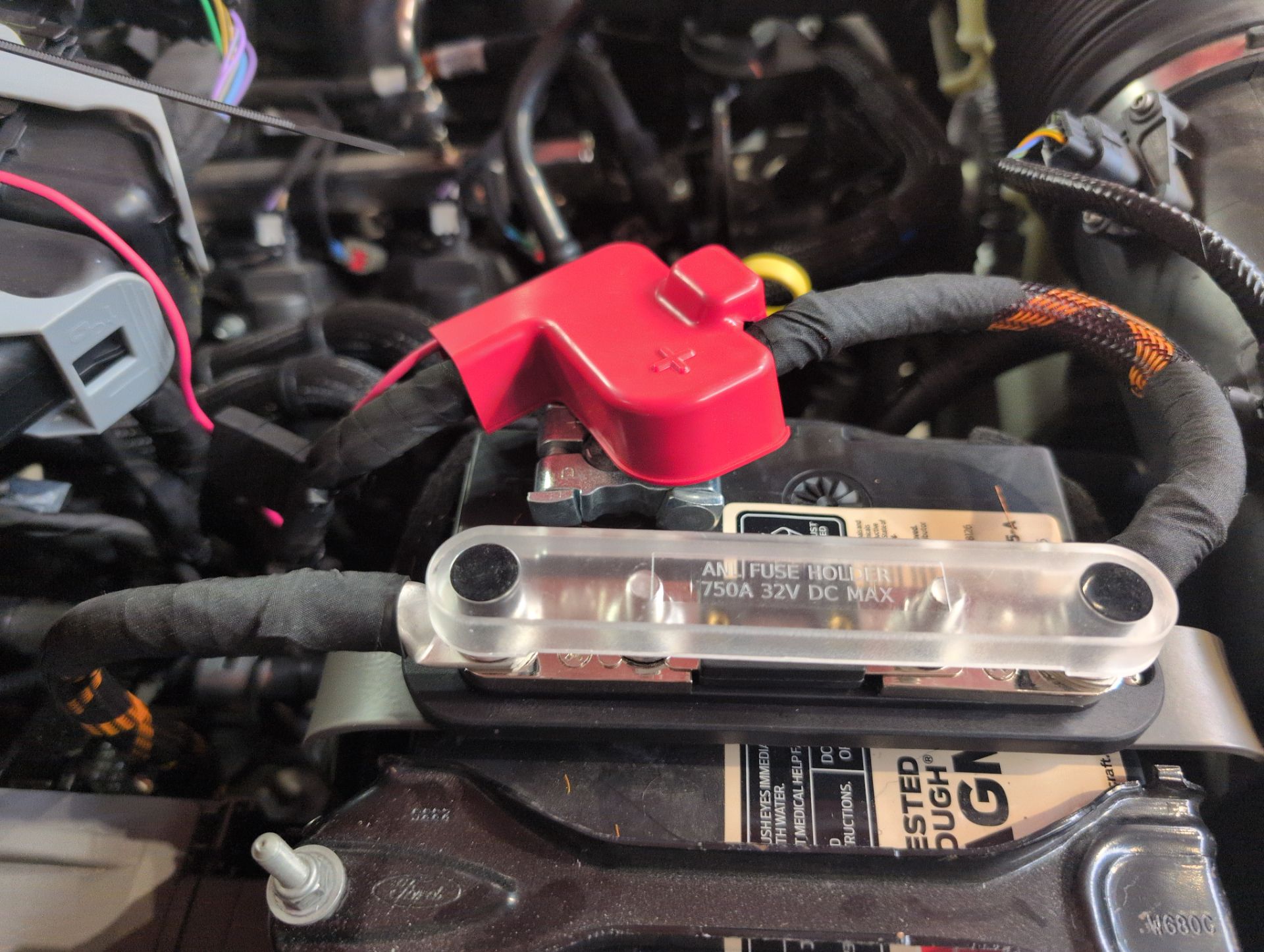 Engine bay with a clear-cover fuse block and a red battery terminal cover