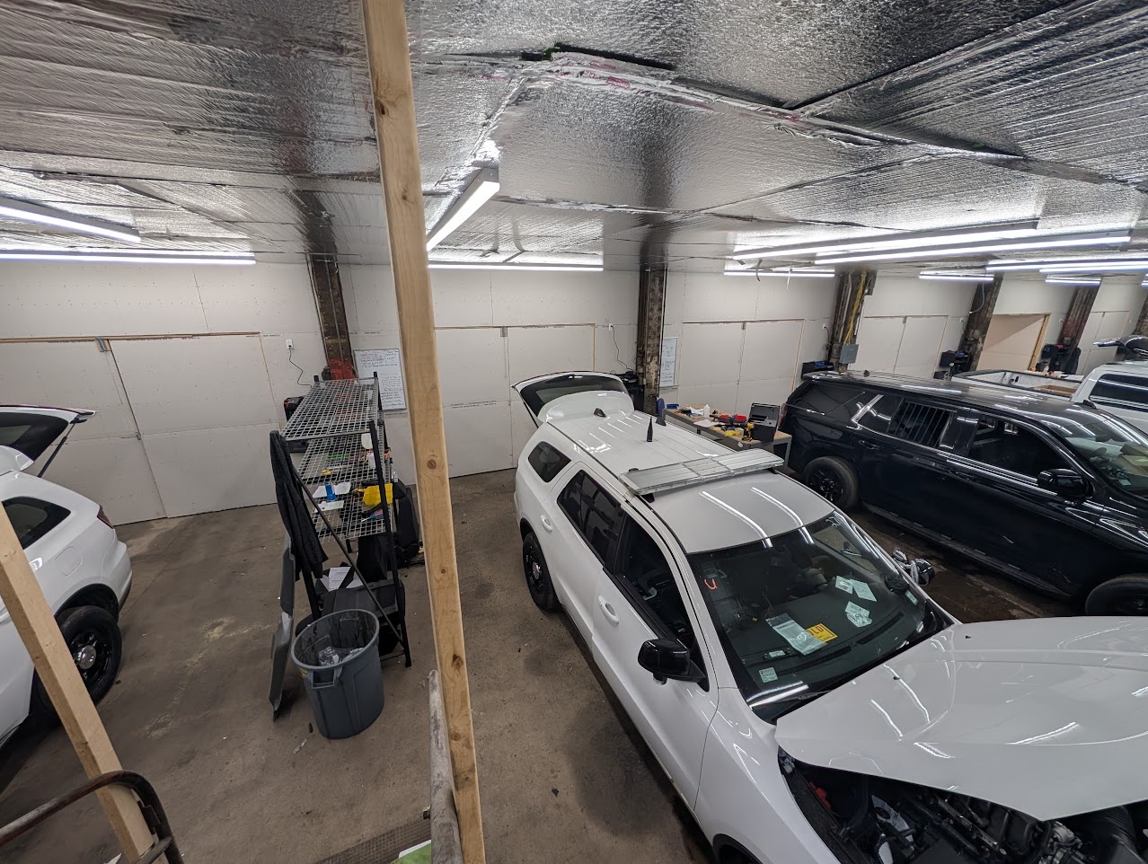 Shop bay with several white police SUVs in different stages of a build